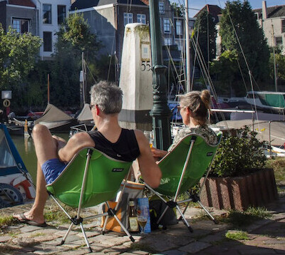 Twee mensen op klapstoeltjes aan de haven